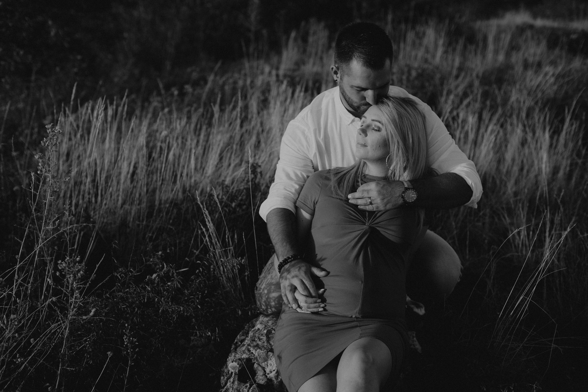 femme enceinte et son mari enlacées dans les herbes folles